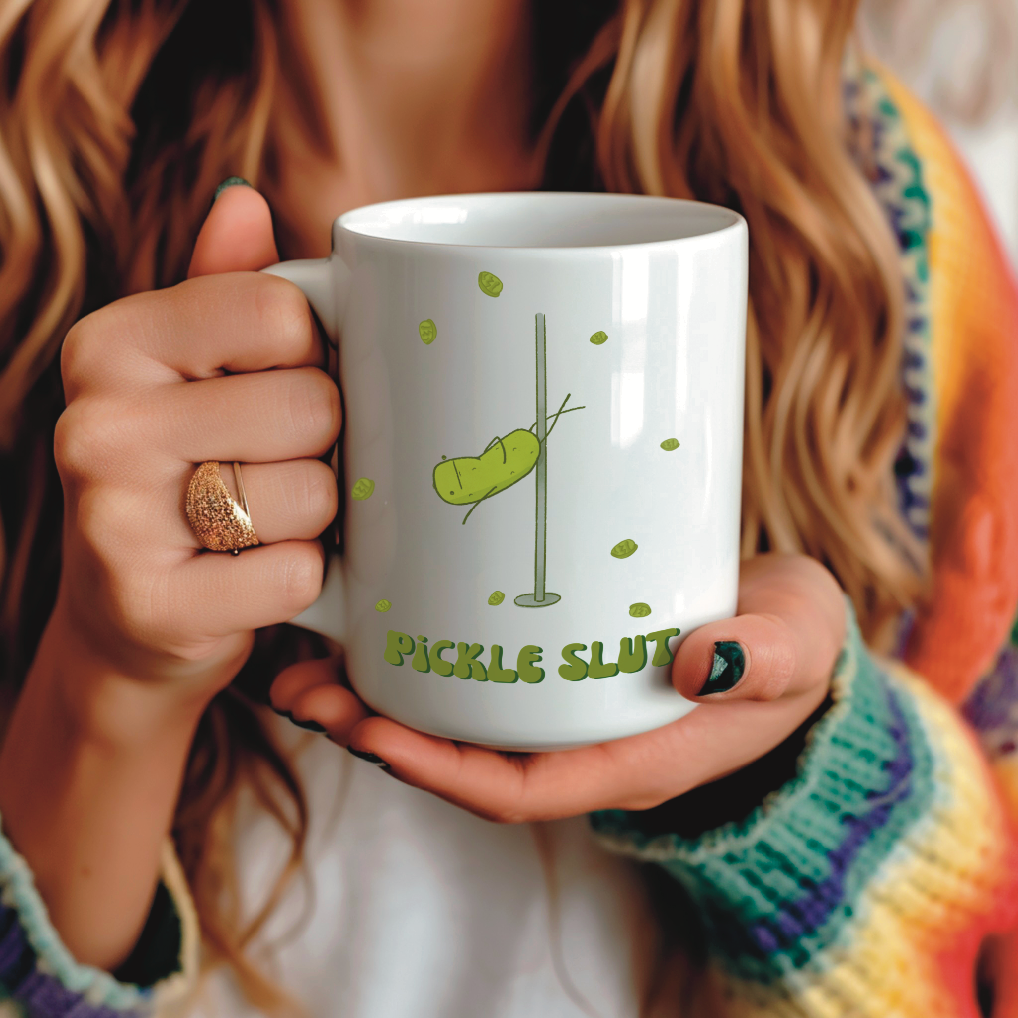 a pickle mug featuring a funny illustration of a cute pickle character pole dancing for pickle chips and text that says "pickle slut" is held by a woman in a rainbow sweater