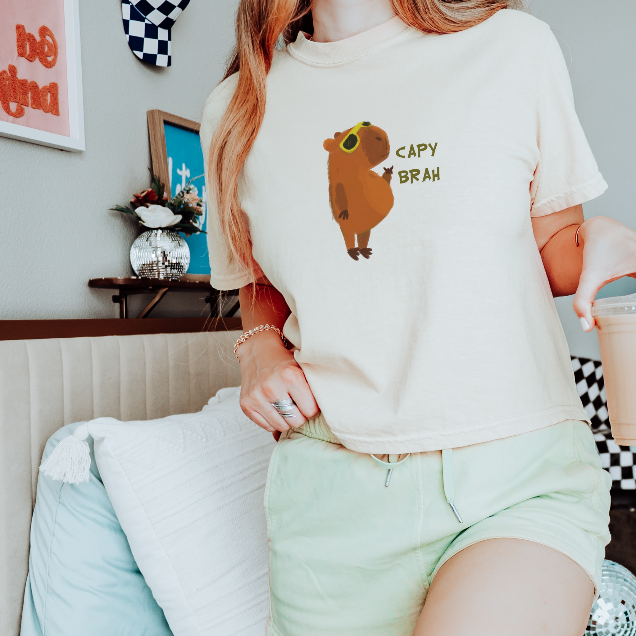 An ivory boxy fit t-shirt featuring a graphic of a capybara with the text 'CAPY BRAH' on the front.