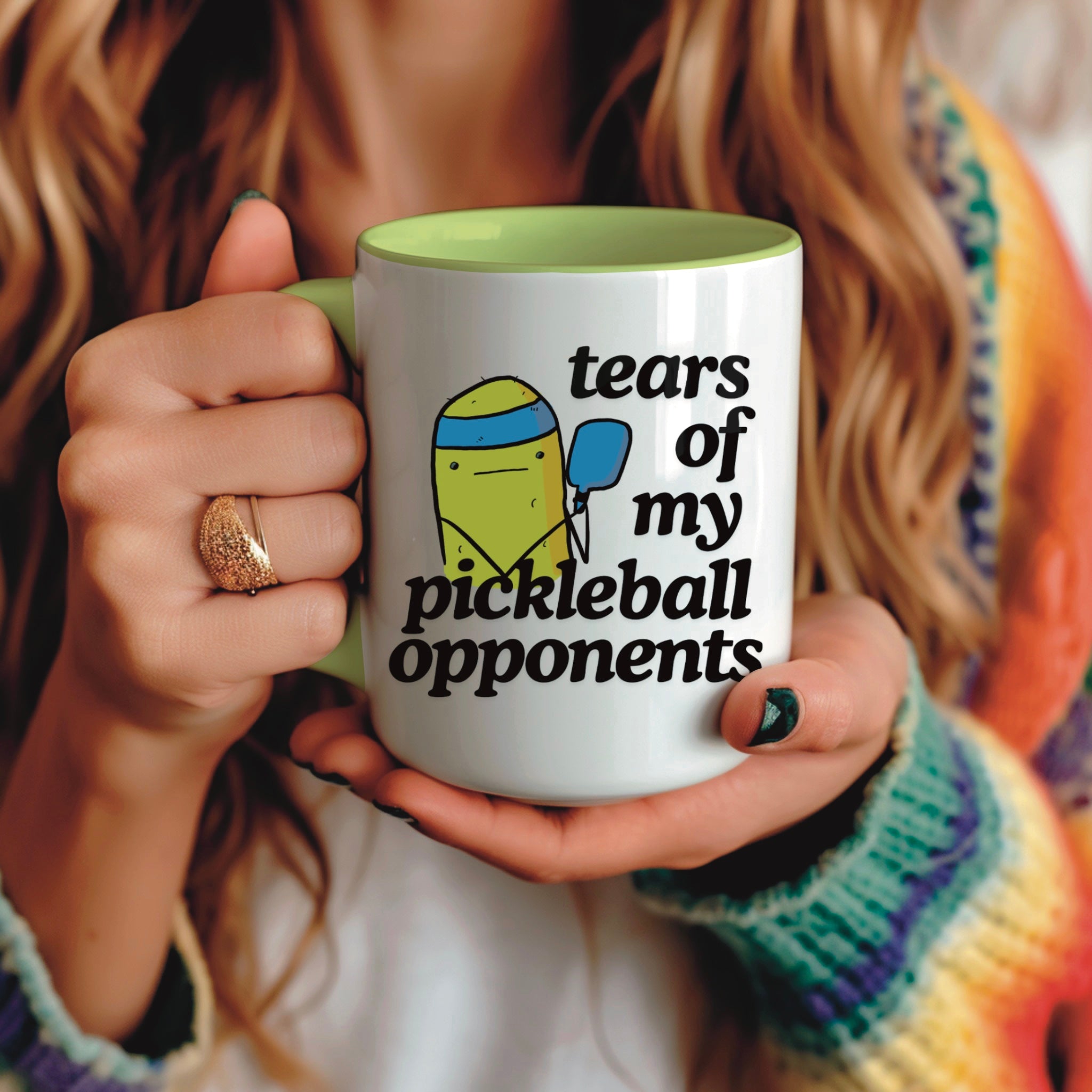 view of a woman holding a pickle ball mug with a funny quote that says "tears of my pickle ball opponents" with cute illustration of a pickle holding a blue pickle ball paddle