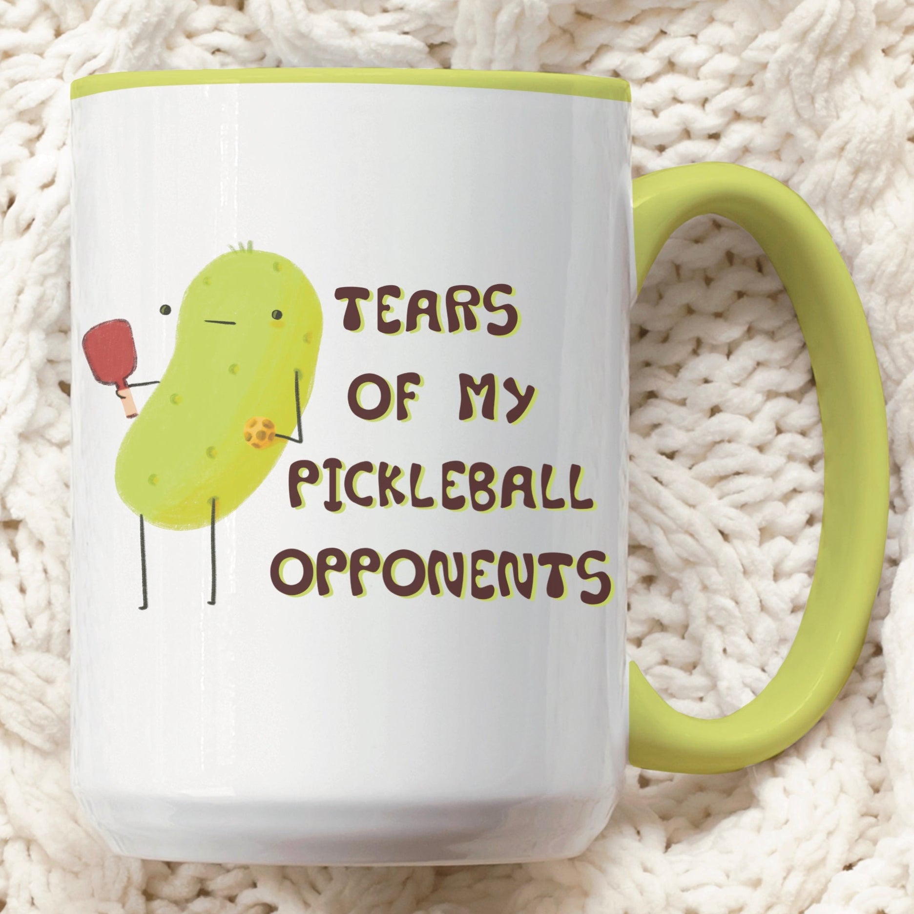 front view of a pickleball mug with funny quote that says "tears of my pickleball opponents" next to illustration of a pickle holding a pickleball and paddle