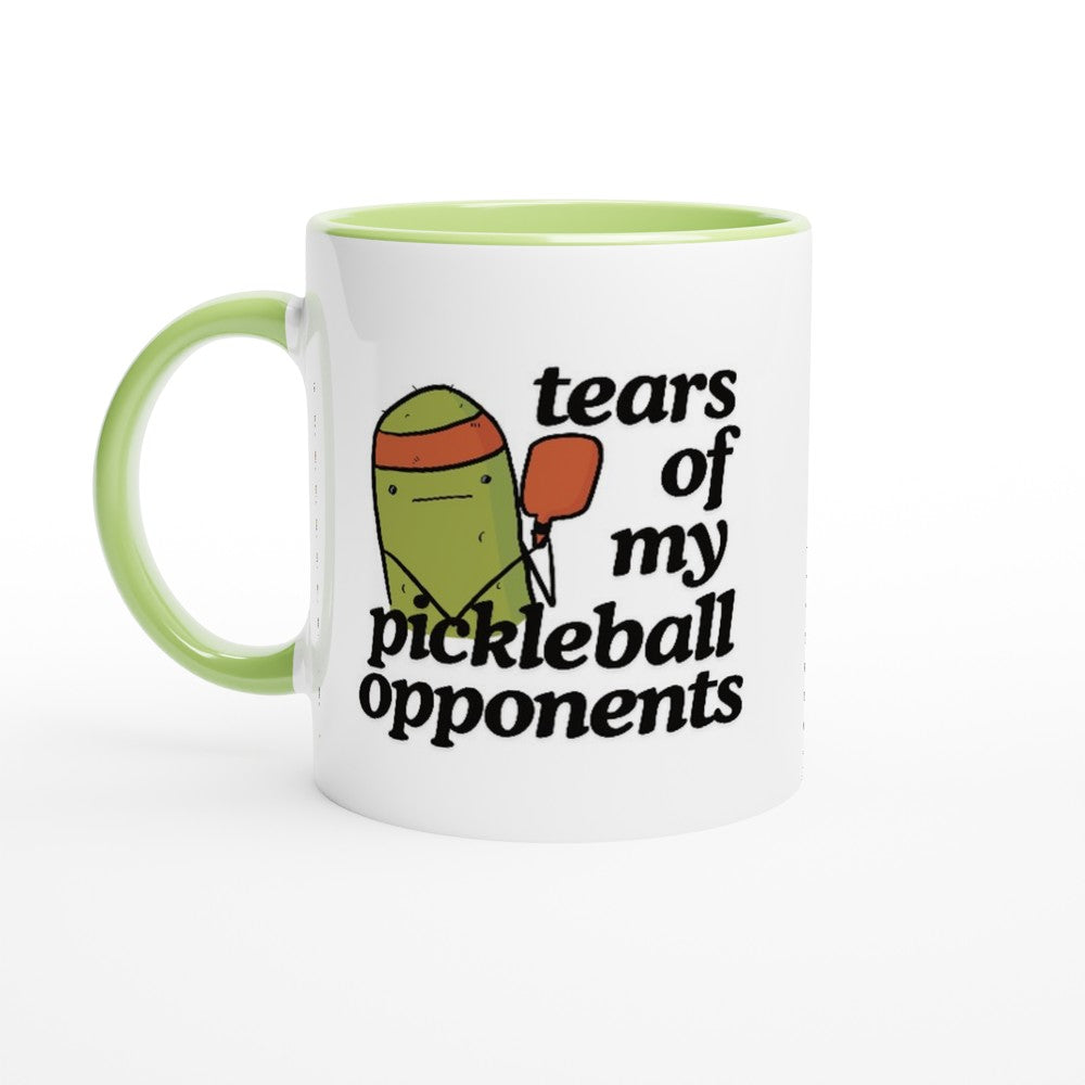 front view of a pickleball mug with a quote that says "tears of my pickleball opponents" with cute illustration of a pickle holding a red pickleball paddle