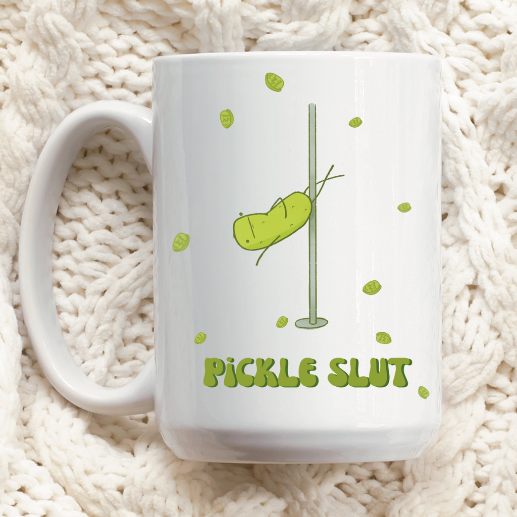 a pickle mug featuring a funny illustration of a cute pickle character pole dancing for pickle chips and text that says "pickle slut" is displayed over a quilted tablecloth
