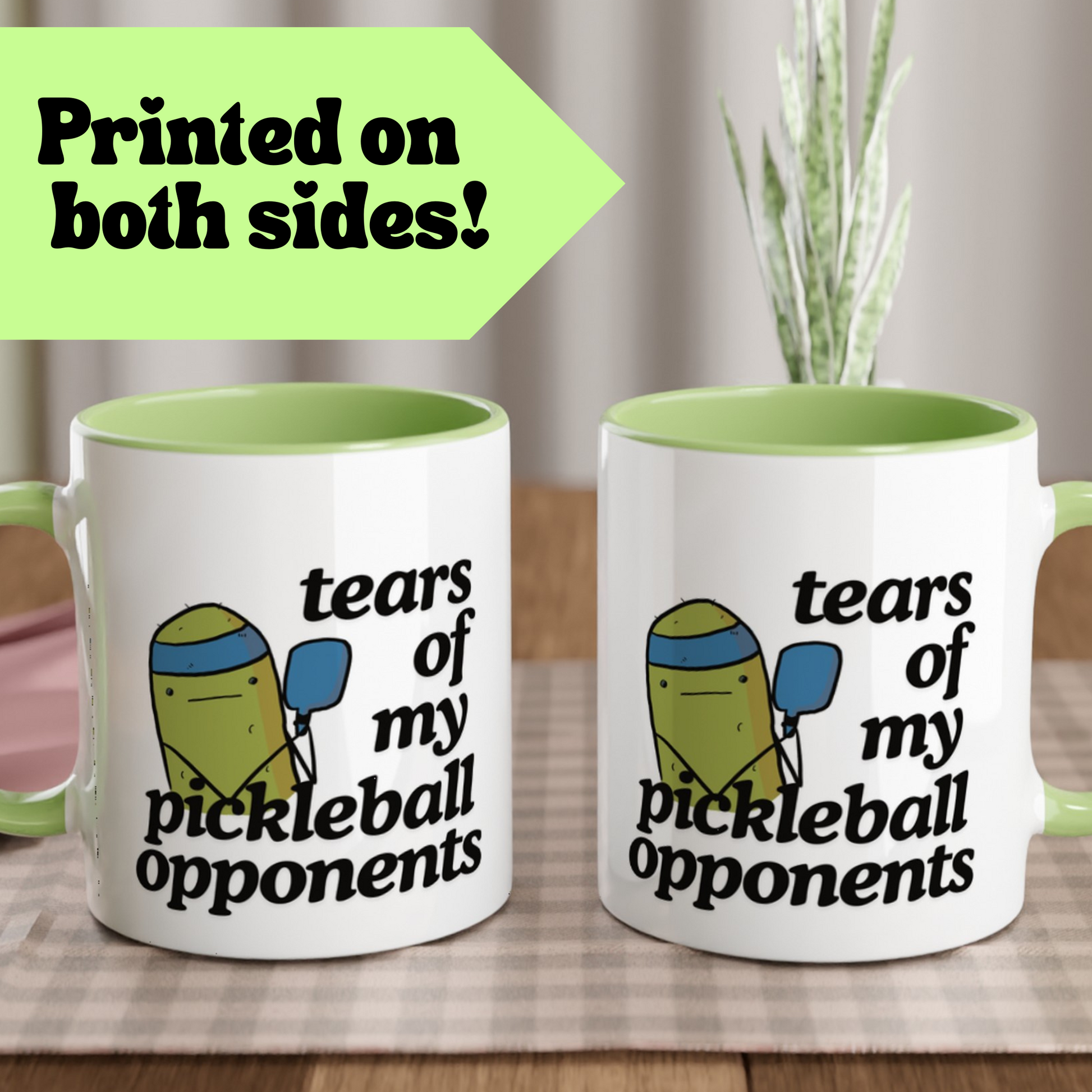 front view of a pickleball mug with a quote that says "tears of my pickleball opponents" with cute illustration of a pickle holding a blue pickleball paddle