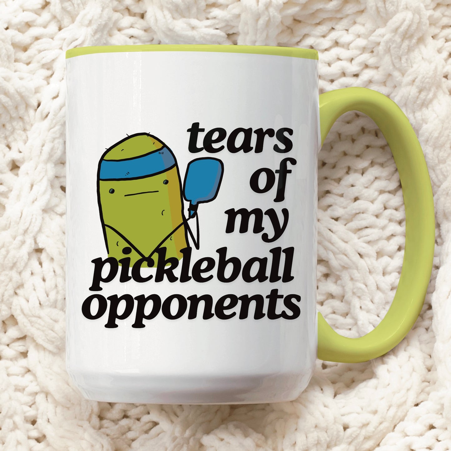 front view of a pickleball mug with a quote that says "tears of my pickleball opponents" with cute illustration of a pickle holding a blue pickleball paddle