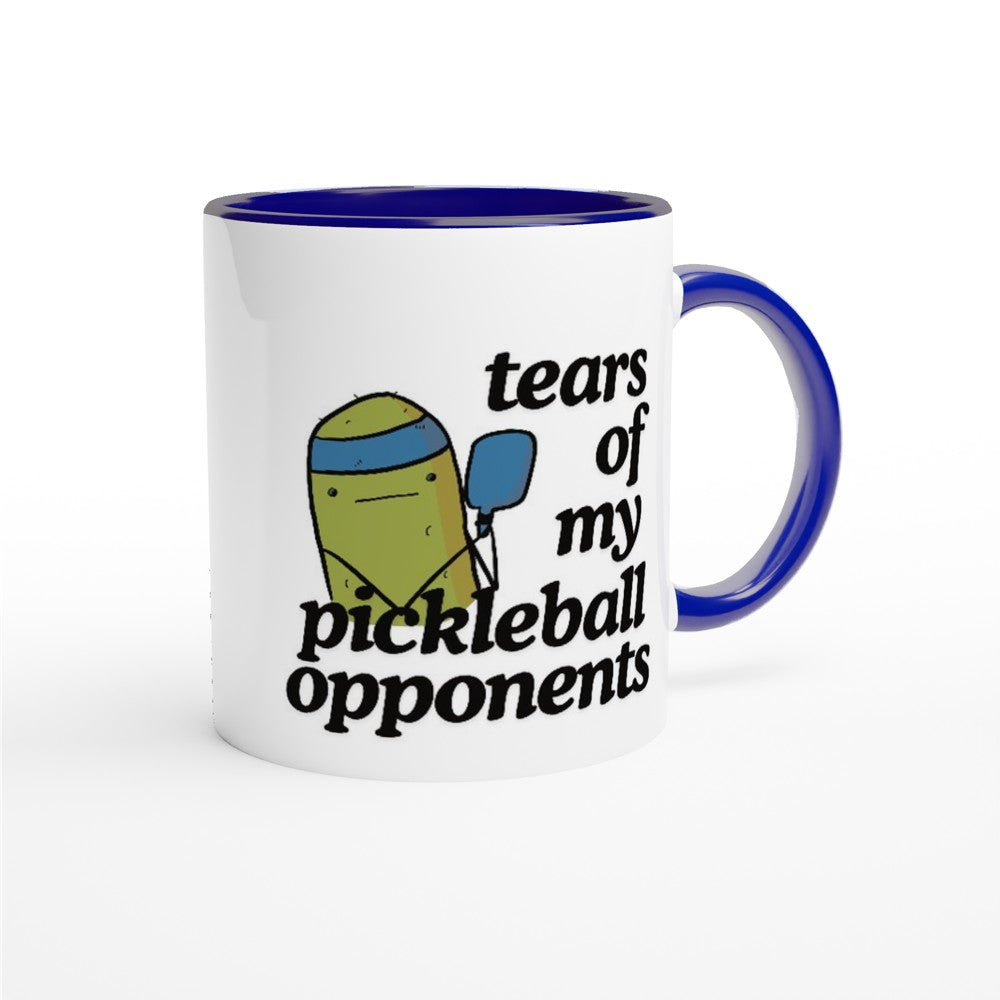 front view of a pickleball mug with a quote that says "tears of my pickleball opponents" with cute illustration of a pickle holding a blue pickleball paddle