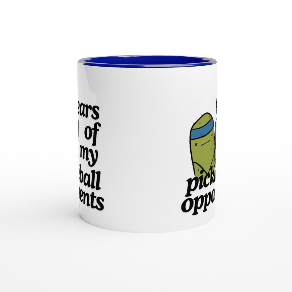side view of a pickle ball mug with a funny quote that says "tears of my pickle ball opponents" with cute illustration of a pickle holding a blue pickle ball paddle