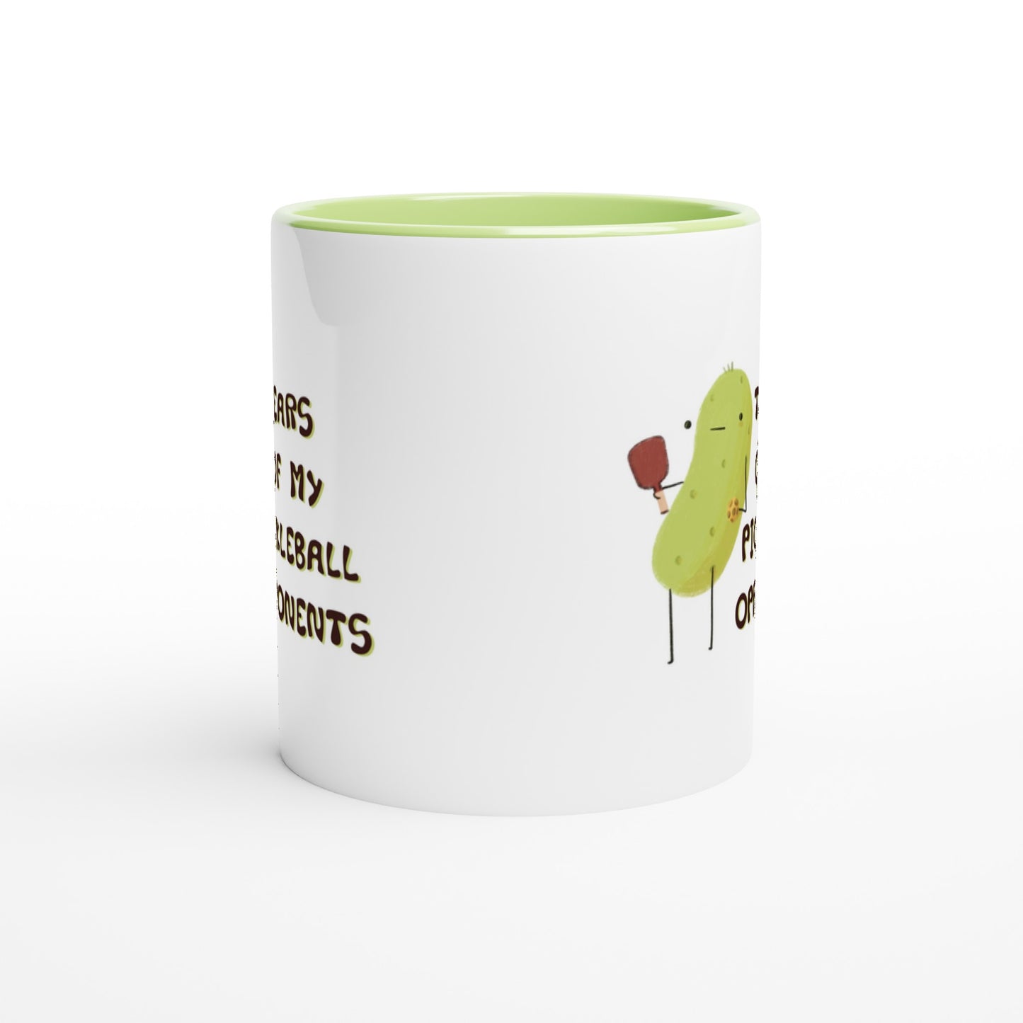 side view of a pickleball mug with funny quote that says "tears of my pickleball opponents" next to illustration of a pickle holding a pickleball and paddle