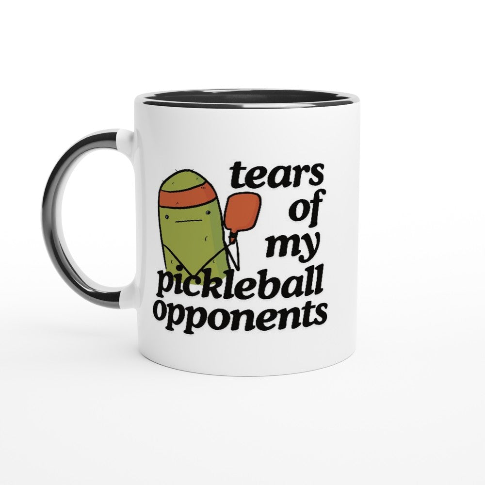 front view of a pickleball mug with a quote that says "tears of my pickleball opponents" with cute illustration of a pickle holding a red pickleball paddle