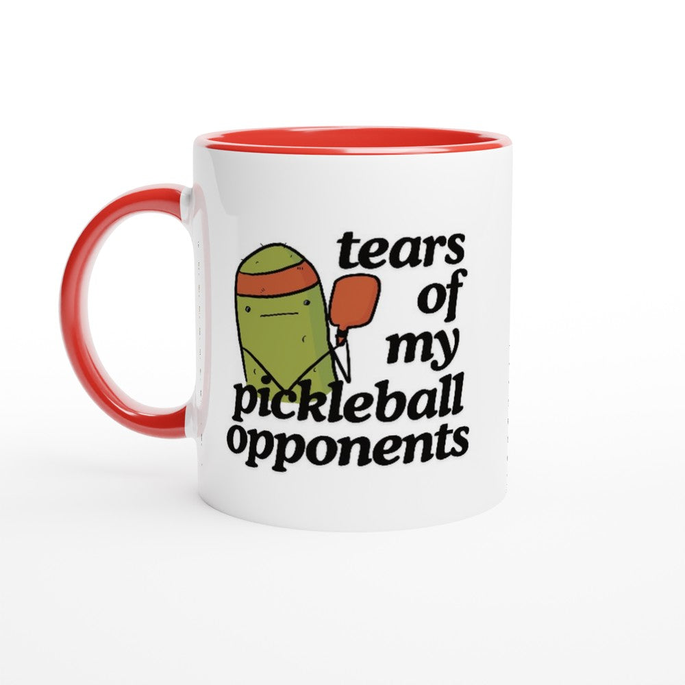 front view of a pickleball mug with a quote that says "tears of my pickleball opponents" with cute illustration of a pickle holding a red pickleball paddle